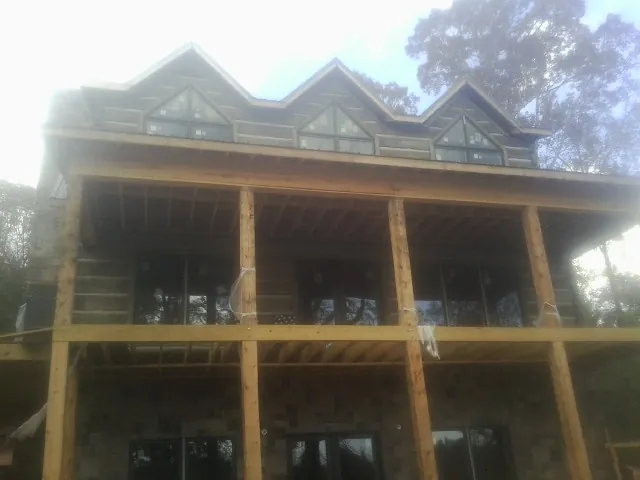 Dormers and porch framing on a large log home under construction — Roof Coating work by our crew in New Iberia