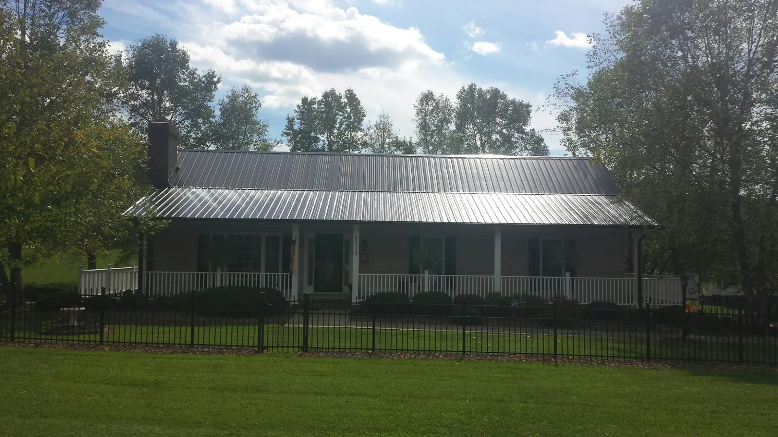 Gray metal roof on a brick ranch with a full width front porch — Gutter Guard Installation work by our crew in New Iberia