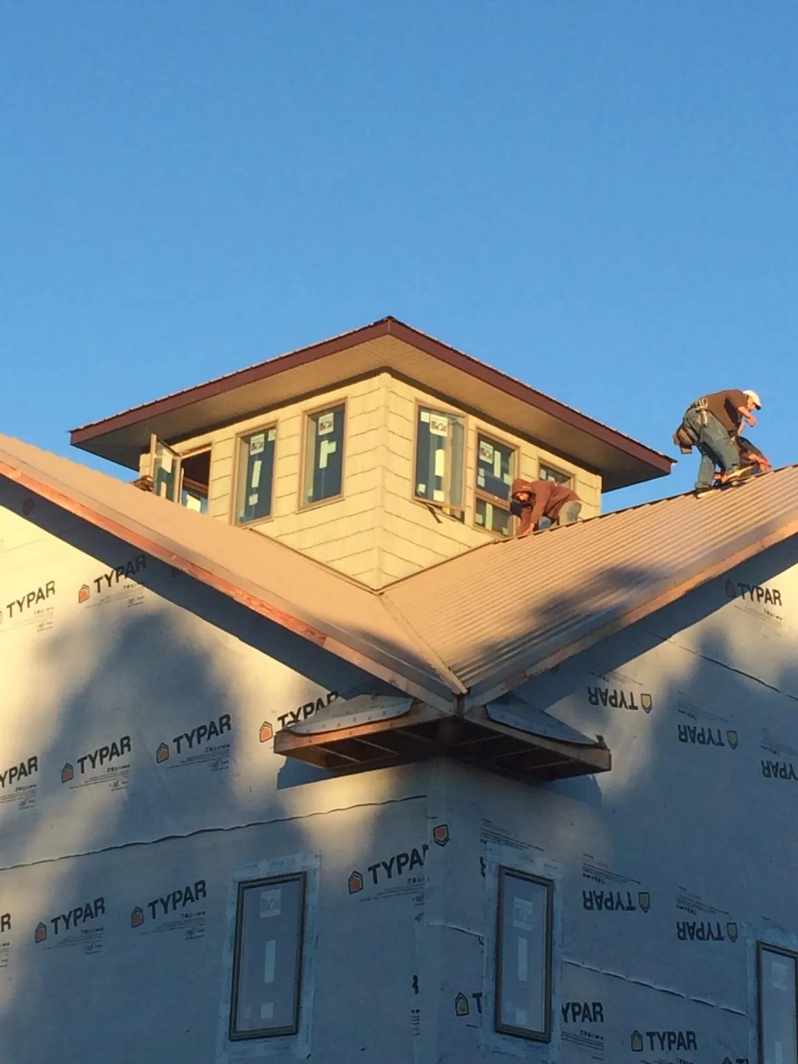 Roofers working around a rooftop cupola on a new metal roof at sunset — Roof Waterproofing in New Iberia by Roofing Brothers